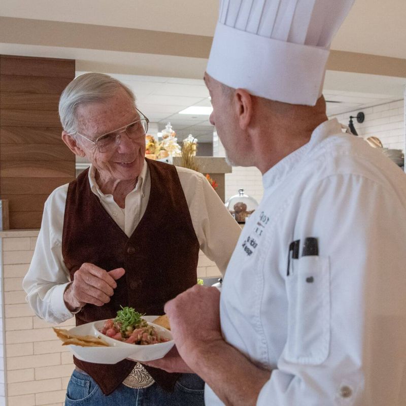 Clermont Park Senior Living Community in Denver, CO - older man and chef discuss meal square