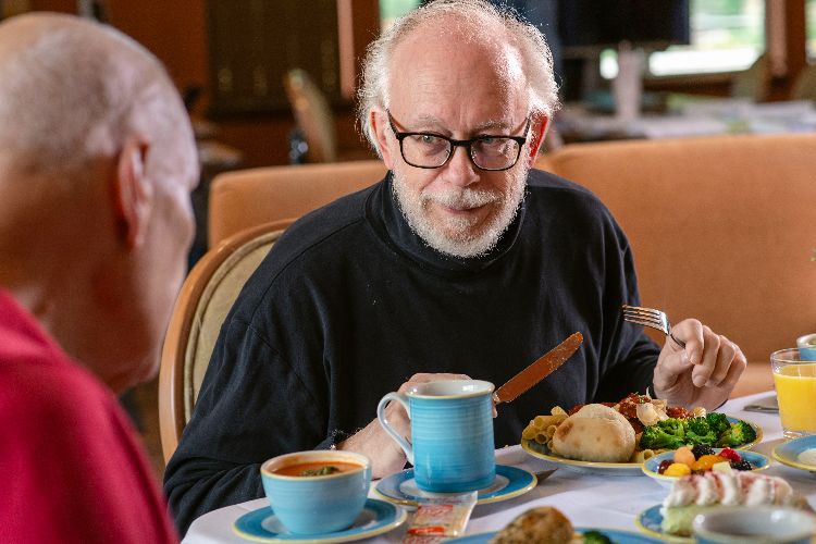 residents talking over meal Clermont Park Senior Living Community in Denver, CO - residents talking over meal